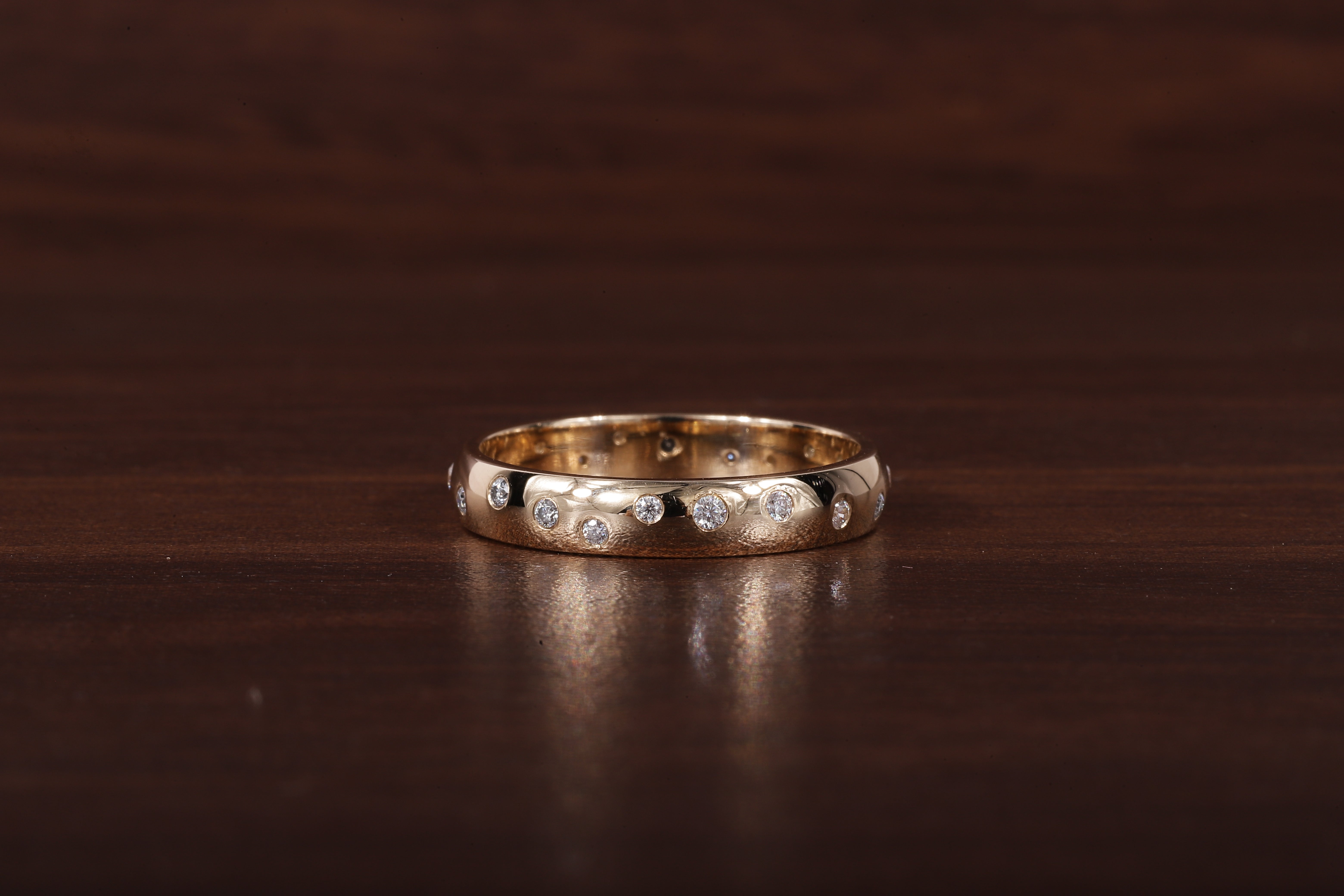 A gold band ring with a row of small clear stones