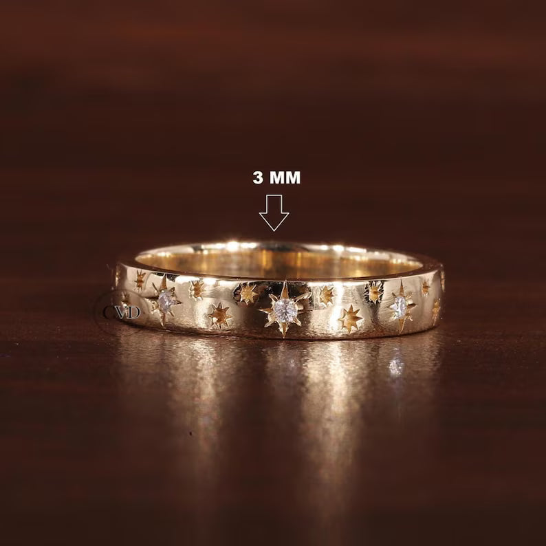 Gold ring with star designs on a dark brown background