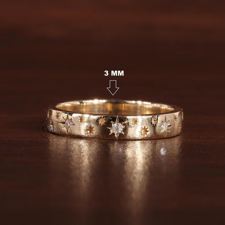 Gold ring with star designs on a dark brown background